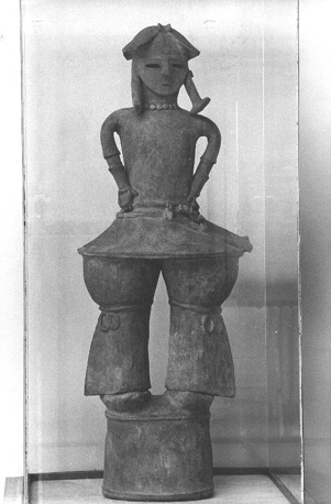 Beeld van een krijger, met een kleed aan en een helm op, staande op een zogenaamde klei-cilinder of "Haniwa"