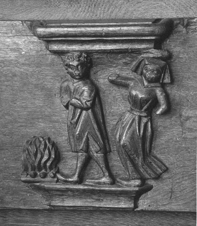 Koorbanken, detail: misericorde met spreekwoord "Iemand het vuur na aan de schenen leggen"