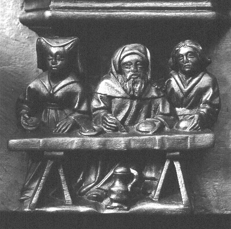 Koorbanken, detail: misericorde met een kuizenaar die tussen een man en een vrouw aan tafel zit