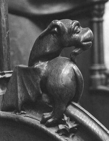 Koorbanken, detail: knop met fantasiedier (met vleugels en geitensik) dat kop naar achteren wendt