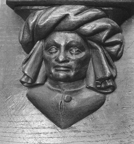 Koorbanken, detail: misericorde met menselijk hoofd bedekt met een opgeknoopte doek
