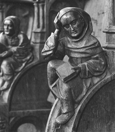 Koorbanken, detail: knop met een zittende monnik die een boek in zijn linkerhand houdt