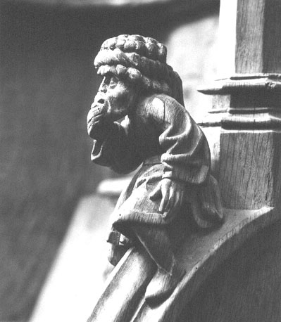Koorbanken, detail: knop met een zittende man die een tulband en aan lang gewaad draagt