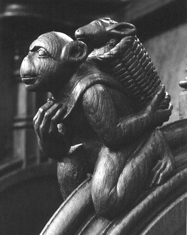 Koorbanken, detail: figuur met een apenkop draagt een mand met een schaap op zijn rug