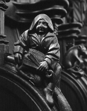Koorbanken, detail: een zittende man met een nijptang