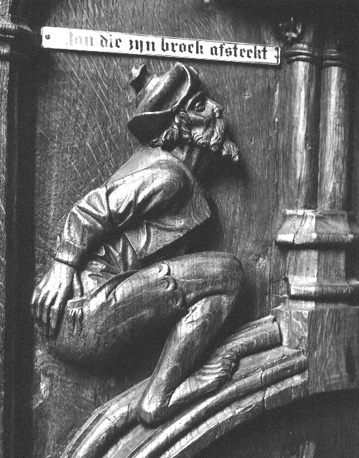 Koorbanken, detail: gehurkte man die met rechterhand zijn broek omlaag trekt