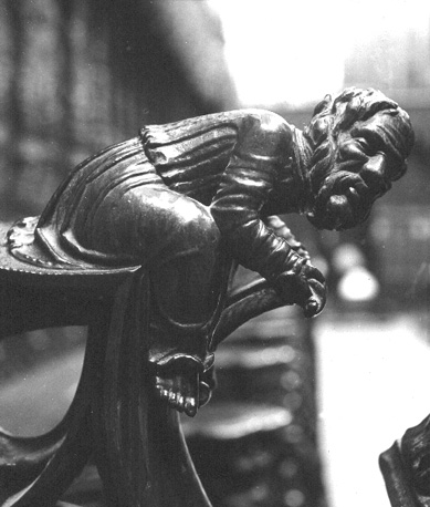 Koorbanken, detail: knop met een zittende man die voorover leunt