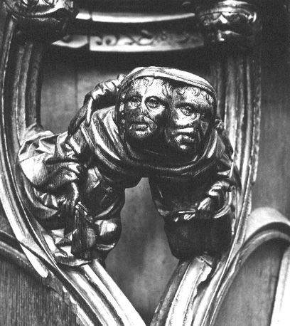 Koorbanken, detail: knop met twee mannen die hun hoofden in dezelfde capuchon hebben