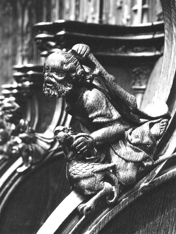 Koorbanken, detail: knop met een man die een vogel wil slaan met een knuppel