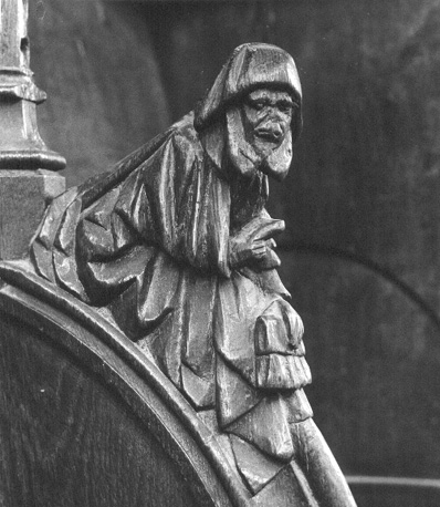 Detail koorgestoelte; Figuur met hoofdkap op en soort tas in de hand