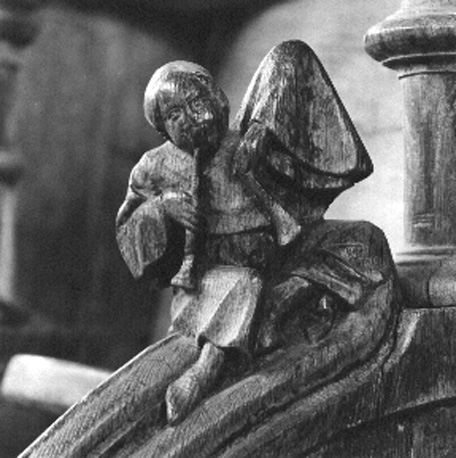 Koorgestoelte, detail: Zittend menselijk figuur met twee fluiten (of trompetten ?)