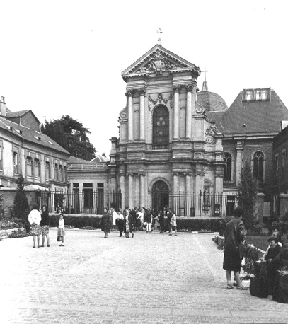 Voorzijde van klooster aan het eind van een plein met mensen