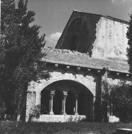 Zicht op kloostergang en westelijke facade van de église Notre-Dame, vanuit het zuidwesten
