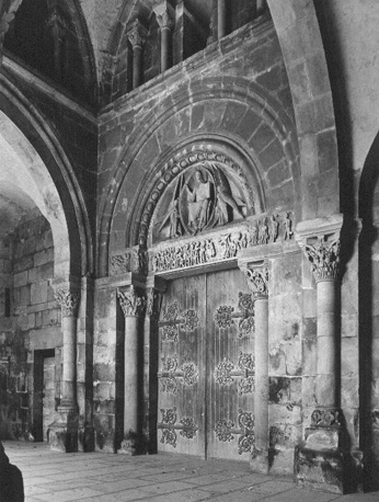 Westelijke zijde, narthex; in timpaan: Tronende Christus, een spreek-gebaar makend en met boek in de hand, aan weerszijden twee engelen met zes vleugels