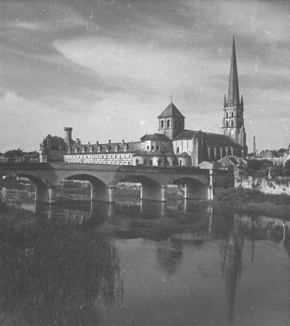 Abdijkerk met voormalige abdij; op voorgrond: een rivier (Gartempe) en brug