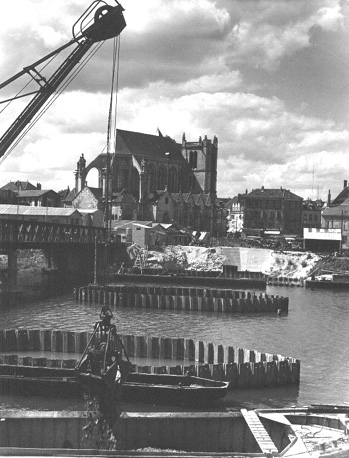Stadsgezicht met kerk (achtergrond) aan de rivier met vrachtboten