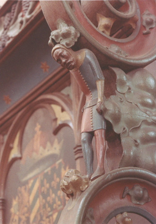 Koor, noordzijde, koorgestoelte, detail: voluutdetail met een wat gebogen staande mannenfiguur