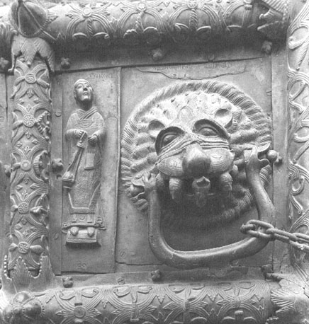 Westfacade, bronzen deuren met reliëfs, detail: diaken met wierookvat; leeuwekop met mensen in zijn muil