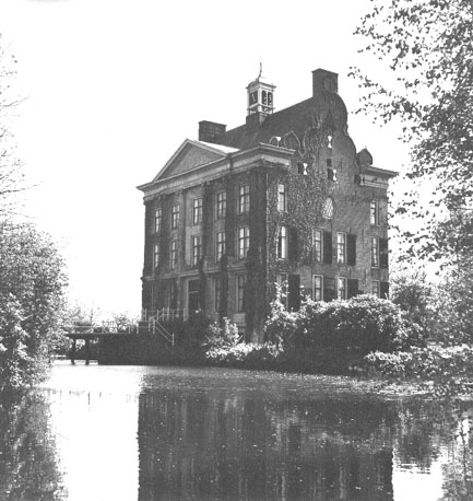 Zicht op voorzijde met puntgevel en brug, omgeven door water