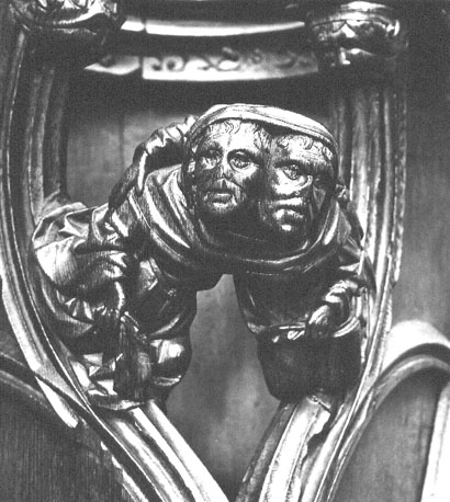 Koorbanken, detail: knop met twee mannen die hun hoofden in dezelfde capuchon hebben