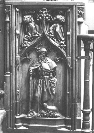 Koorbanken, detail: de kluizenaar H. Antonius met klokje, boek, T-staf, vlammen en varken