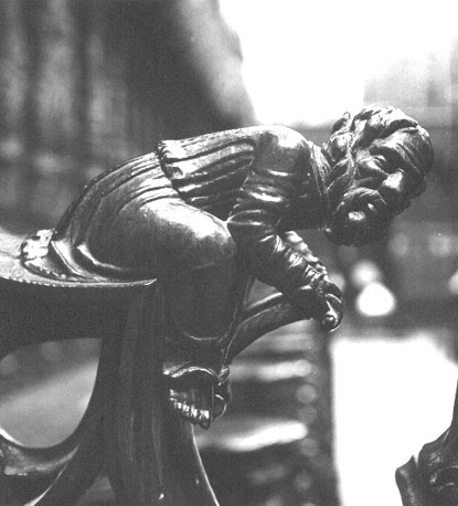 Koorbanken, detail: knop met zittende man met een schild