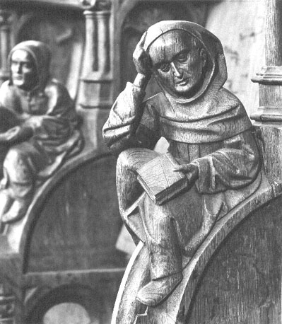 Koorbanken, detail: knop met een zittende monnik die een boek in zijn linkerhand houdt