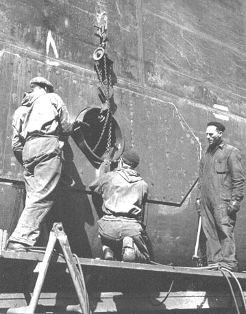 Drie mannen aan het werk in de scheepsbouw
