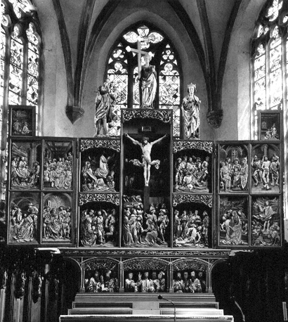Koor, hoofdaltaar, Passieretable: Christus hangend aan het kruis (midden), twaalf panelen aan weerszijden, drie beelden bovenop (sint Christophorus, sint Helena, sint Margareta)