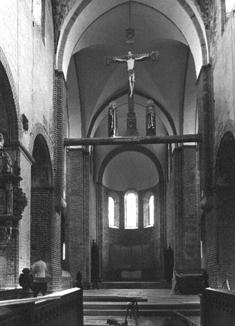 Zicht op viering, koor en (in triomfboog) Christus aan het kruis met Maria en Johannes aan weerszijden, vanuit het westen