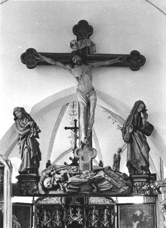 Boven ingang van het koor: Triomfkruis, gekruisigde Christus, met Maria en Johannes aan weerszijden van het kruis; gebeente van Adam aan de voet van kruis, figuurtje van de stichter.