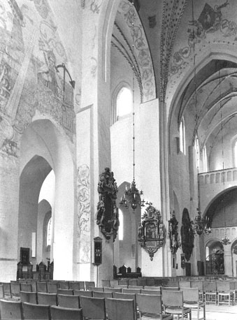 Zuider transept (gedeeltelijk) en zicht in noorder transept vanuit het zuiden; muurschildering (links): heilige Clemens met een anker in zijn linkerhand