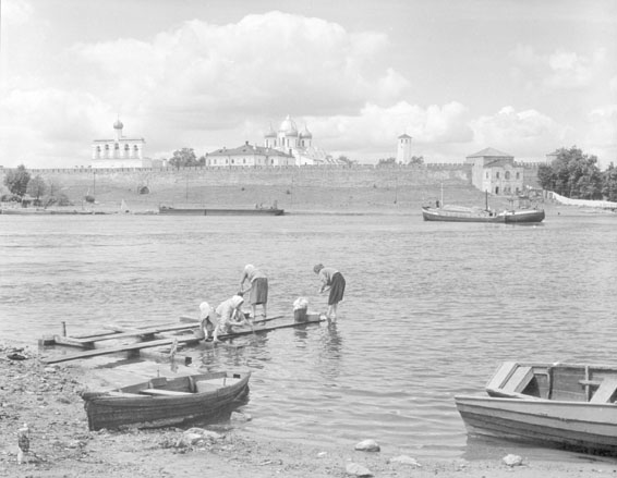 Zicht op stadsmuur, verschillende kerktorens achter de muur, vrouwen doen de was in de rivier