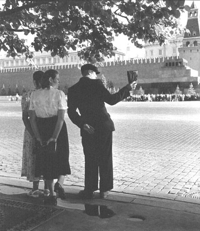 Drie personen kijken naar de muur van het Kremlin en de ingang van Lenin-mausoleum