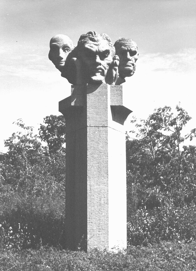 Tooropmonument; gebeeldhouwde koppen op een hoge sokkel, waaronder de kop van Jan Toorop