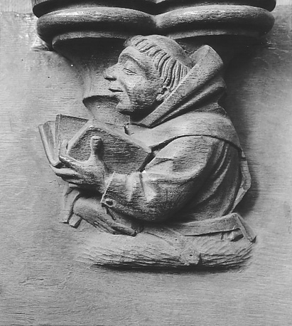 Koorgestoelte, misericorde: monnik met geopend boek in linkerhand, lezend of zingend