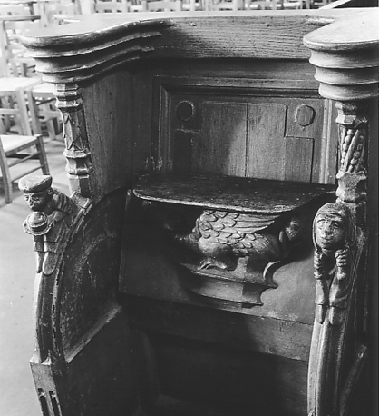 Koorbank, twee menselijke figuurtjes als knoppen op armleuningen; misericorde