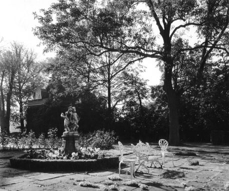 Tuin met tuinmeubels en sculptuur op sokkel