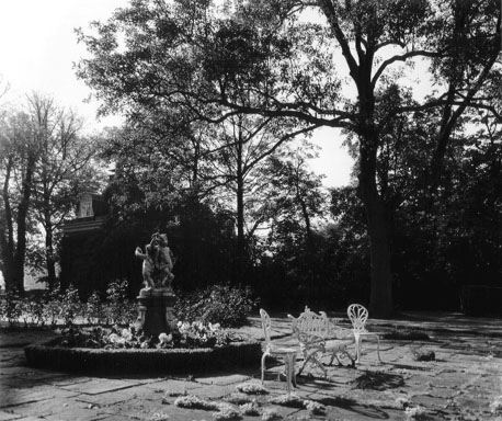Tuin met tuinmeubels en sculptuur op sokkel