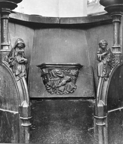 Koorbanken, detail: misericorde met monnik met boek bij een boom. Armleuning: links vrouw met open boek, rechts monnik met een hand op zijn knie.