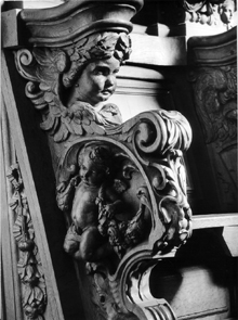 Koorbanken. Detail van wang: engel met guirlandes en engelenhoofd.