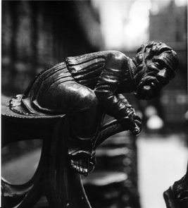 Koorbanken, detail: knop met zittende man die voorover leunt.