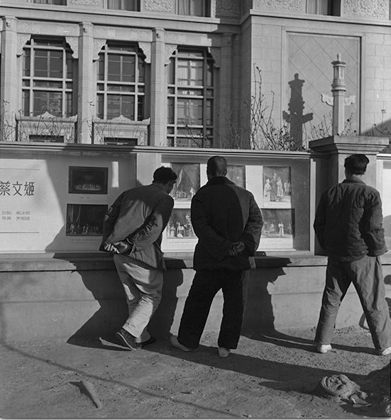 Straatbeeld: drie mannen bekijken porgramma's voor de opera